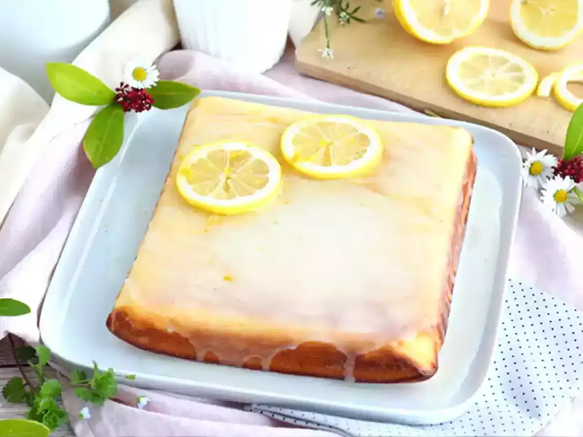 Delicioso brownie de limón cubierto con glaseado y rodajas de limón fresco.