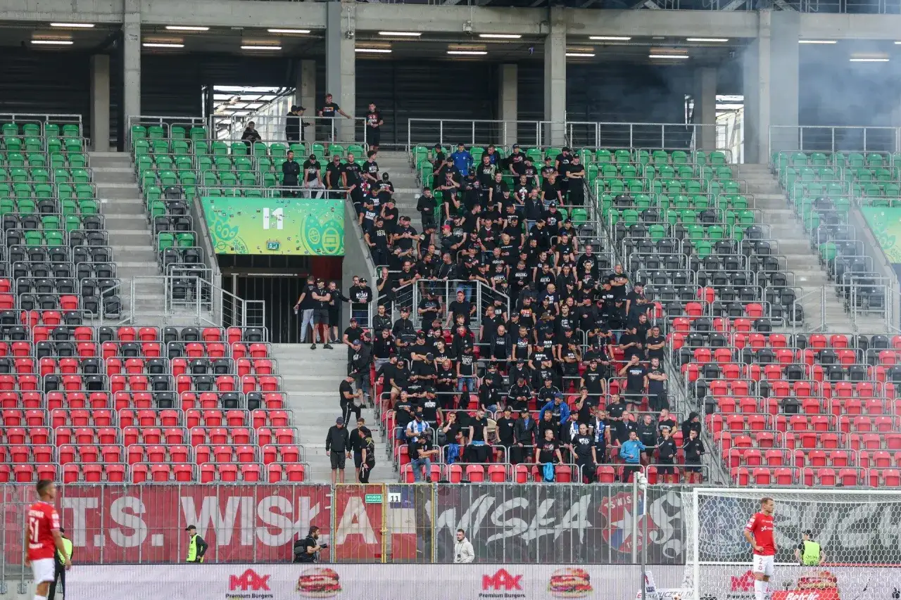Kibice Wisły Kraków i GKS Tychy na trybunach stadionu. Dym unosi się nad sektorem gości.