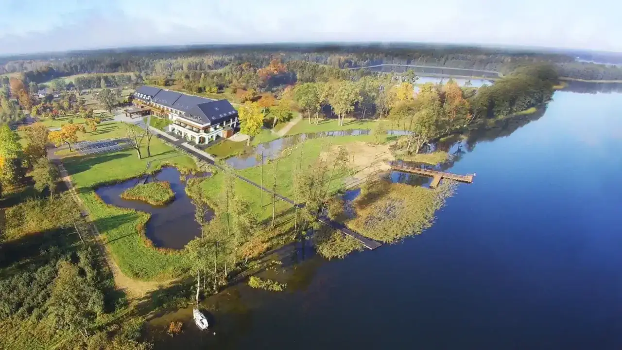 Malowniczy widok na narie resort & spa nad jeziorem, otoczony jesiennym lasem.