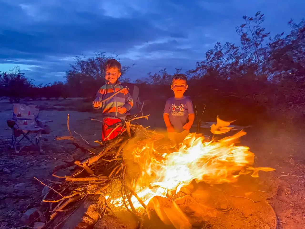 Zwei Jungen genie&szlig;en die Abendd&auml;mmerung am Lagerfeuer. Perfekte camping spiele f&uuml;r einen unvergesslichen Abend.