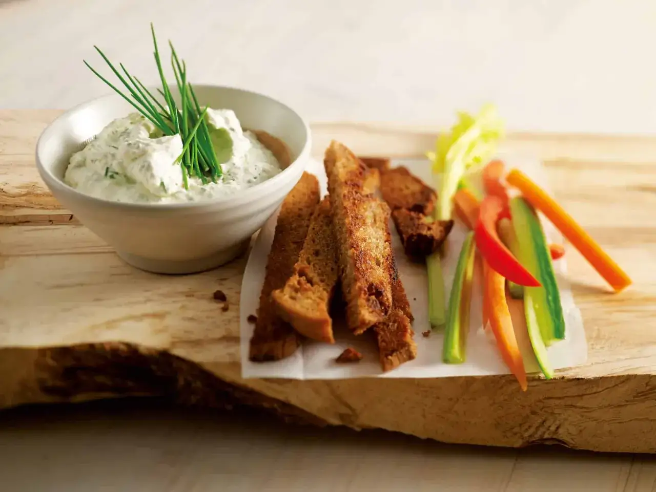 Cremiger Dip mit Kräutern, dazu knusprige Brotscheiben und Gemüsesticks – perfekt für Dips zum Grillen.