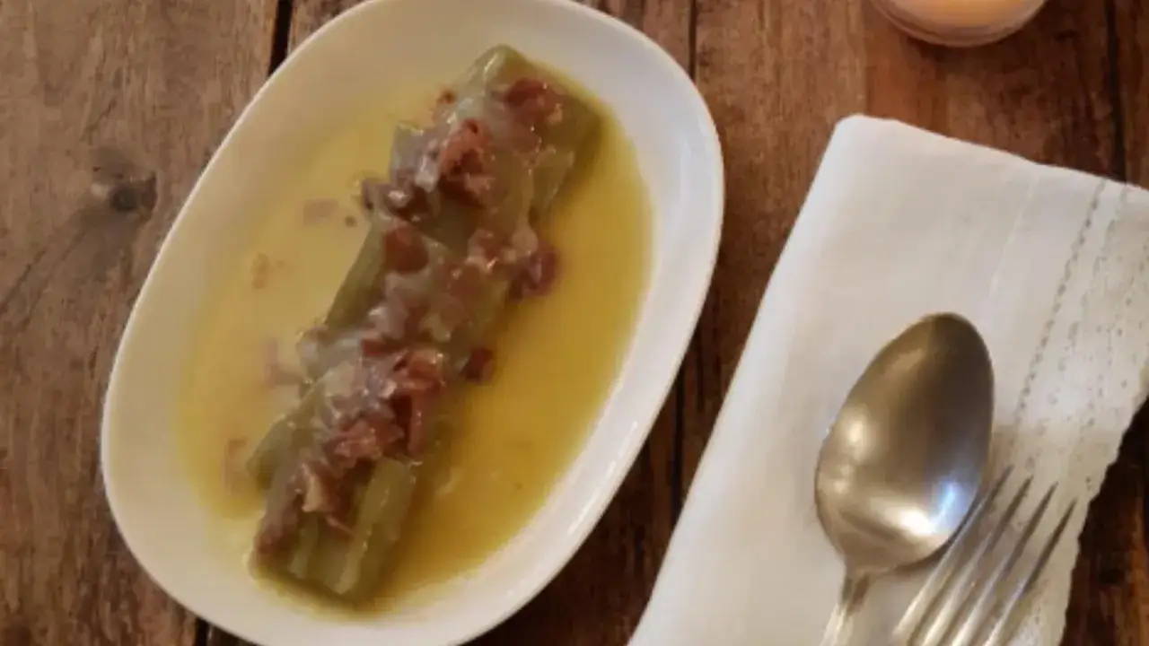 Cardo a la navarra, un plato tradicional con trozos de cardo en una salsa dorada, adornado con jamón.