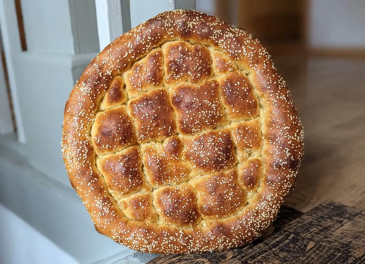 Ein goldbraunes Fladenbrot, bestreut mit Sesam, bereit zum Genie&szlig;en. So einfach ist es, Fladenbrot selbst backen!
