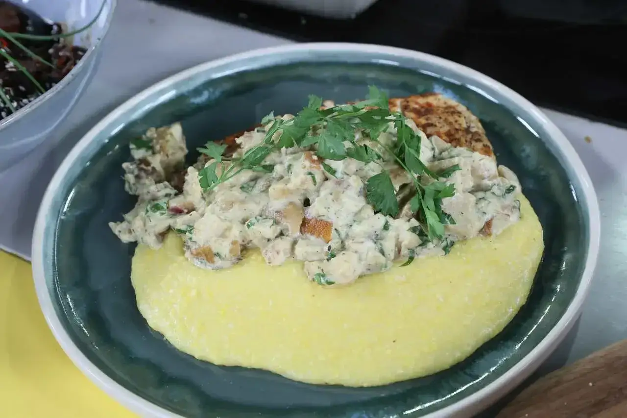 Pyszna polenta co to? Kremowa kaszka kukurydziana z kawałkami kurczaka w sosie, udekorowana natką pietruszki.