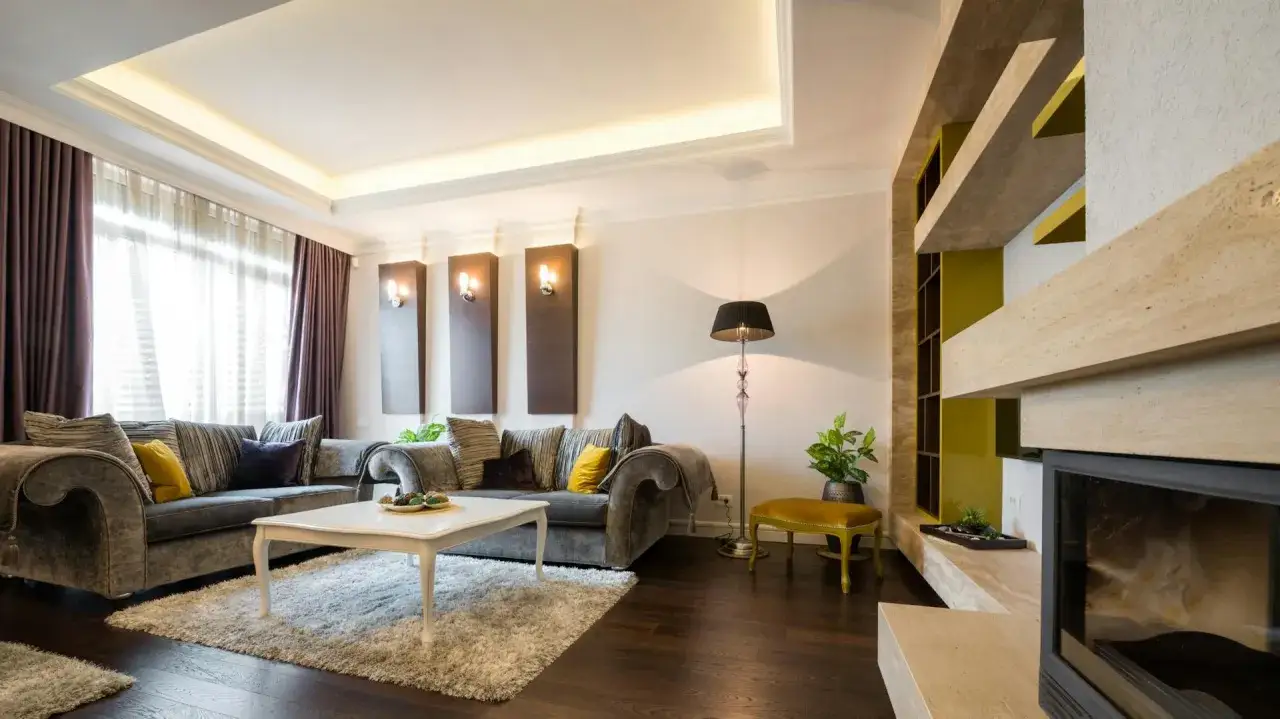 Elegante wohnzimmer decke ideen mit indirekter Beleuchtung, die eine gem&uuml;tliche Atmosph&auml;re schaffen. Ein luxuri&ouml;ses Sofa und ein Kamin laden zum Entspannen ein.