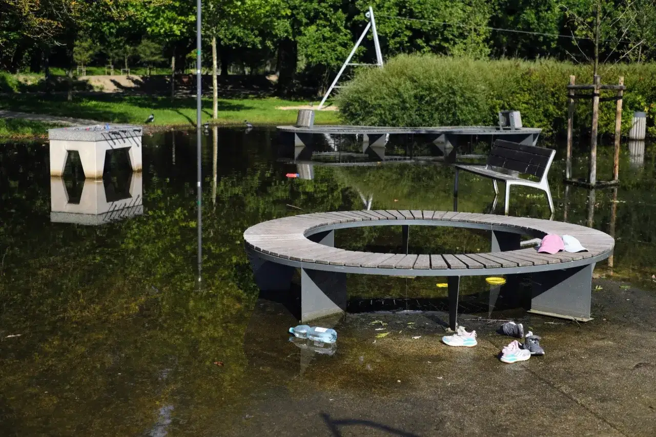 Zalany park wodziczki. Okrągła ławka i stolik do piłkarzyków stoją w wodzie.