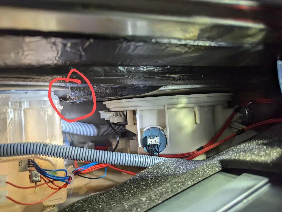 Wyciek pod zmywarką Electrolux, prawdopodobnie przyczyna błędu i30. Widać mokrą izolację i elementy pompy.