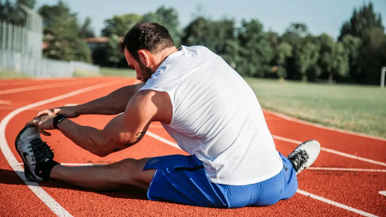 Mężczyzna rozciąga się na bieżni, przygotowując się do biegu na 10 km.