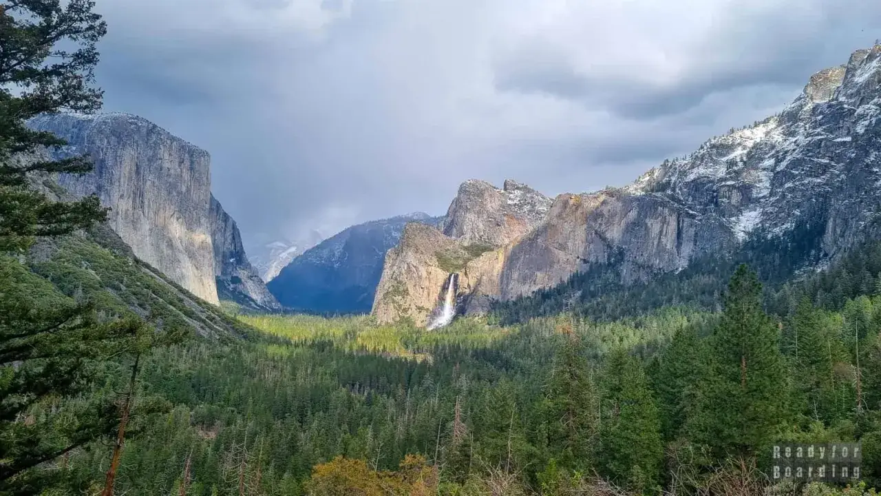 Majestatyczne góry i wodospad w **parku narodowym Yosemite**. Las sosnowy u podnóża skalnych ścian.