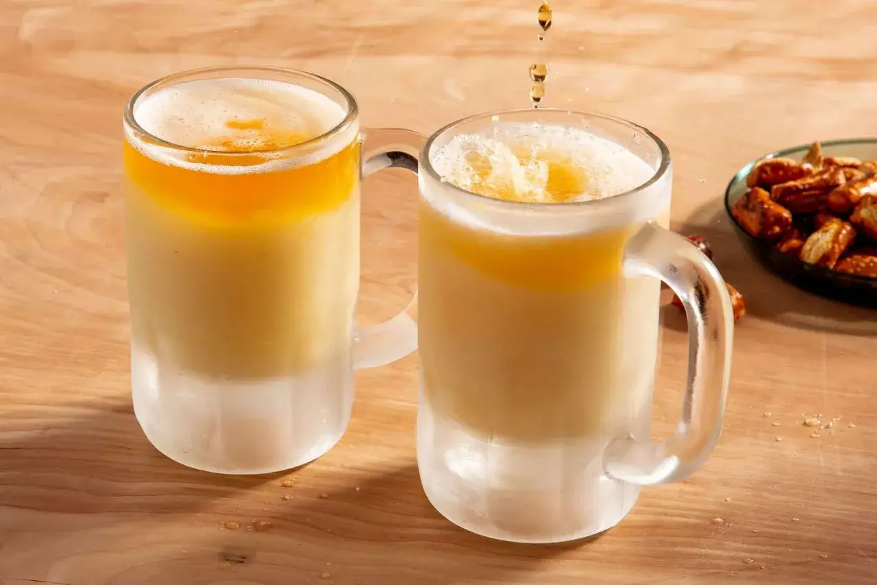 Zwei Gl&auml;ser mit eisgek&uuml;hltem Ginger Beer mit Alkohol und einer Schaumkrone. Daneben eine Schale mit Brezeln.