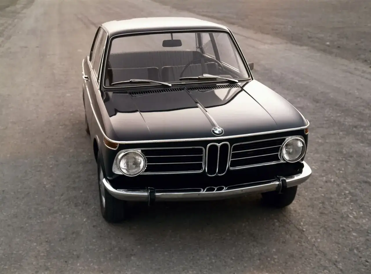 Klasyczny, czarny **BMW 2002** stoi na pustej drodze, gotowy na kolejną podróż.