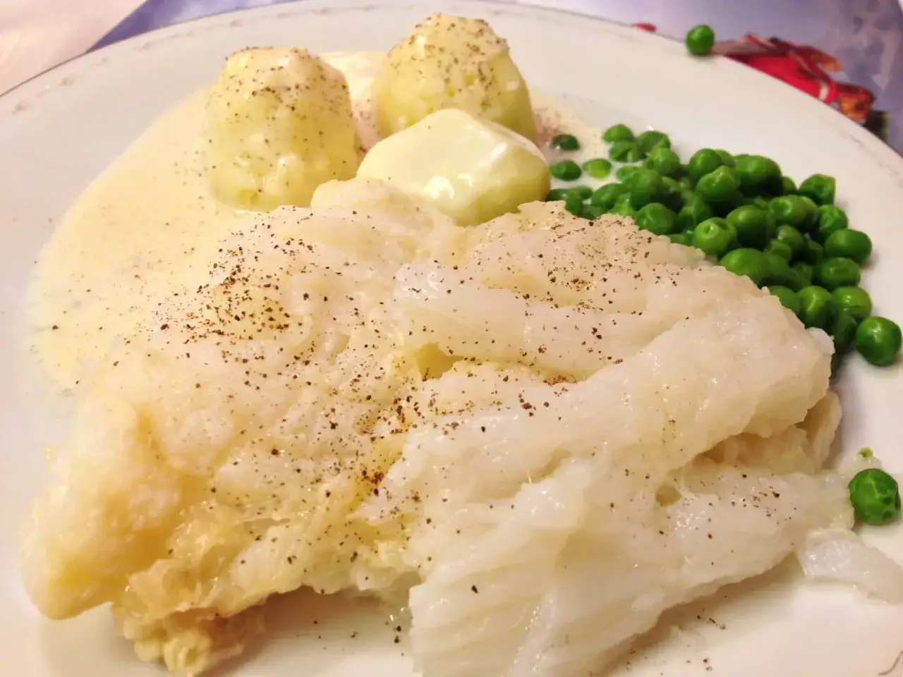 Lutfisk med potatis, ärtor och vit sås. En klassisk svensk rätt, perfekt med ett glas vin till lutfisk.
