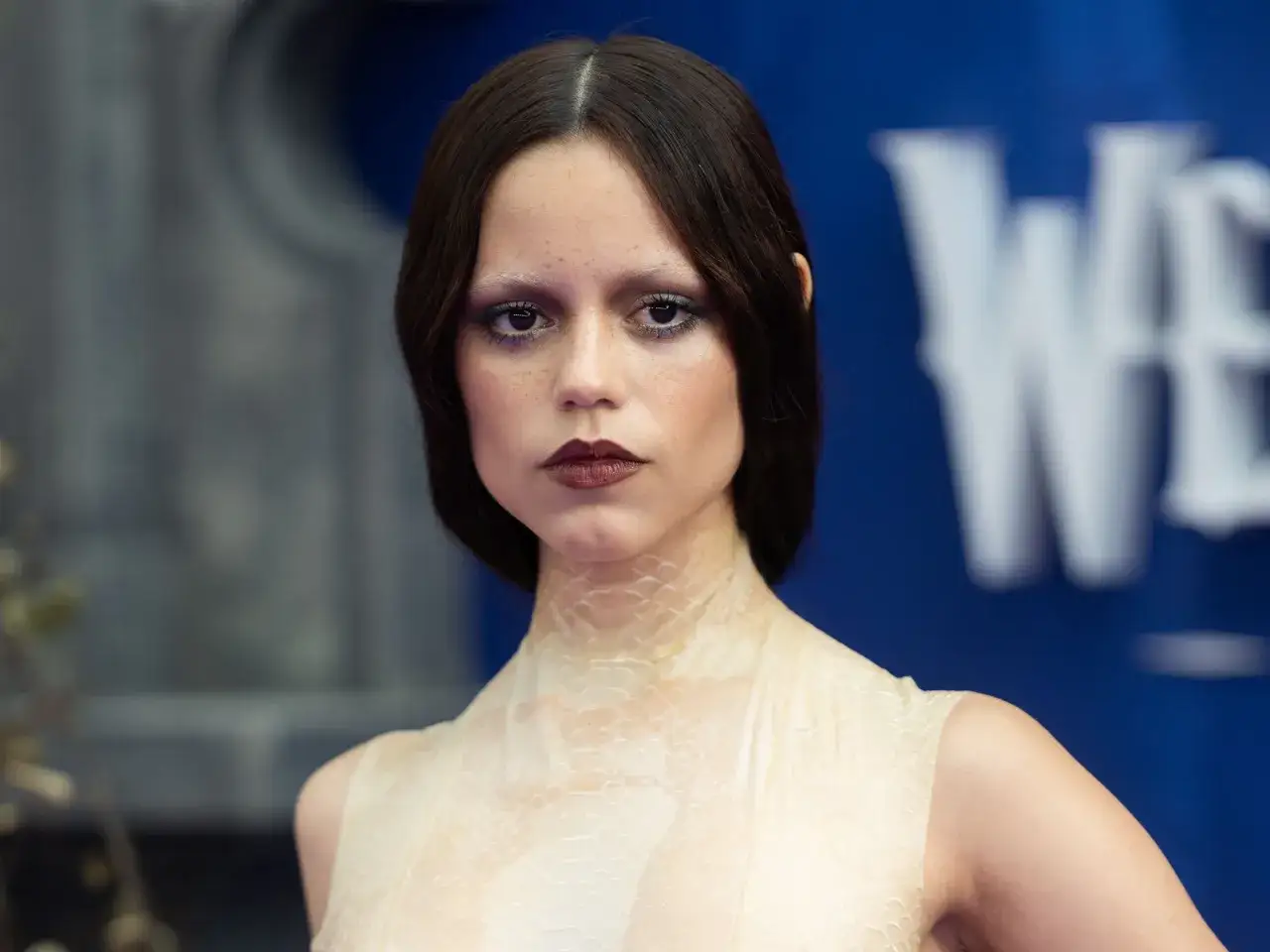 Donna con trucco Halloween semplice: labbra scure, occhi viola e pelle effetto squame.