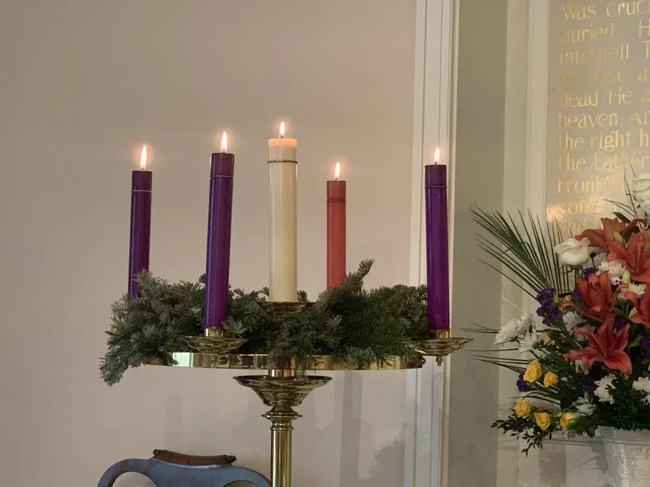 Advent wreath with two purple, one cream, and one red candle lit. The second day of Advent is here, bringing hope.