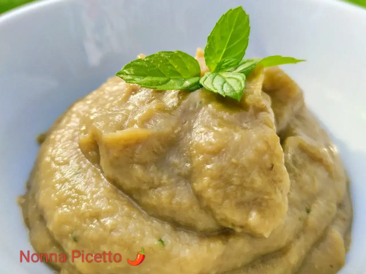 Pesto di melanzane cremoso, guarnito con foglie di menta fresca. Un sapore estivo che ricorda la nonna.