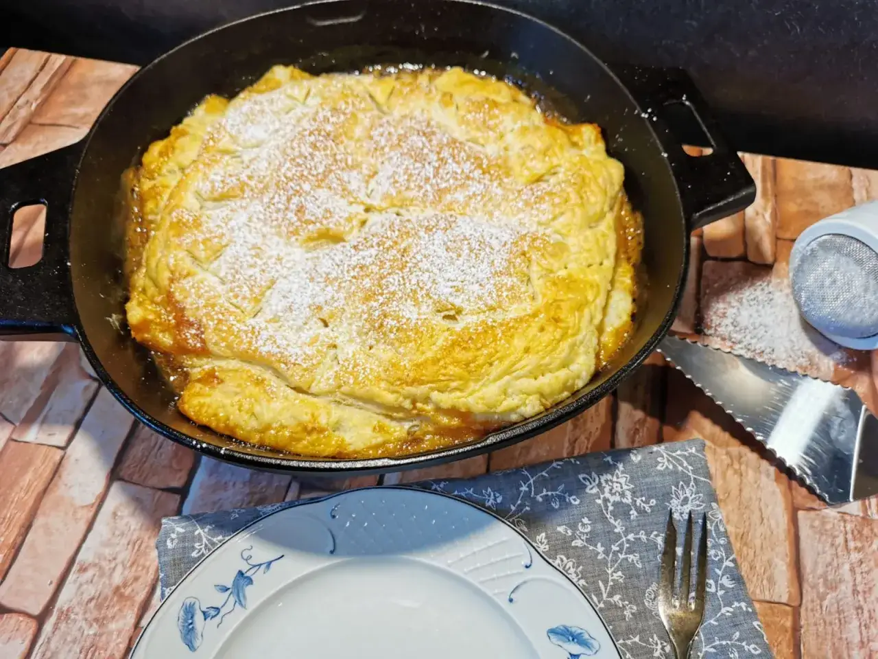 Goldbraune Tarte Tatin mit Puderzucker bestäubt, frisch aus der Pfanne. Ein Genuss für alle Sinne!