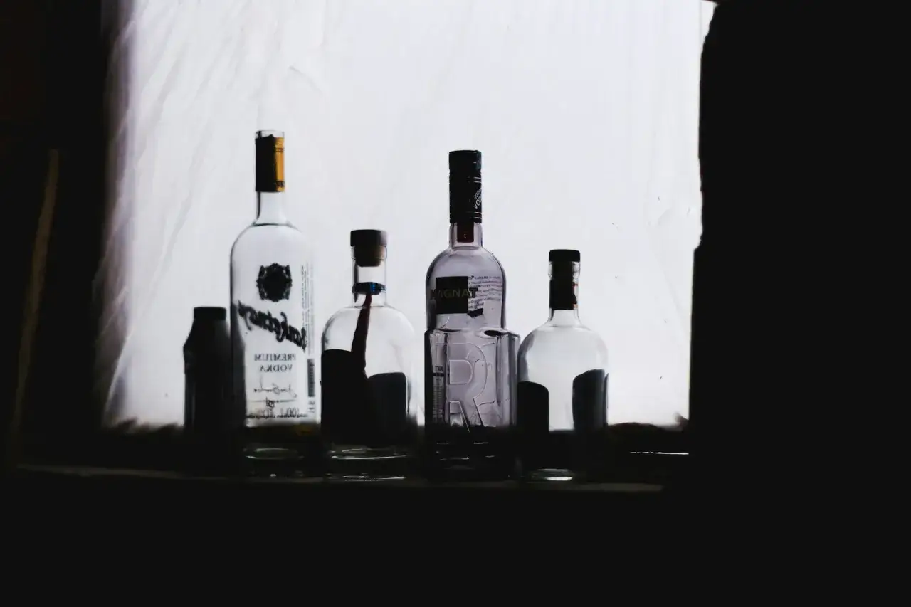 Butelki z alkoholem na tle białej tkaniny. Zastanawiasz się, po jakim czasie od zastrzyku można pić alkohol?