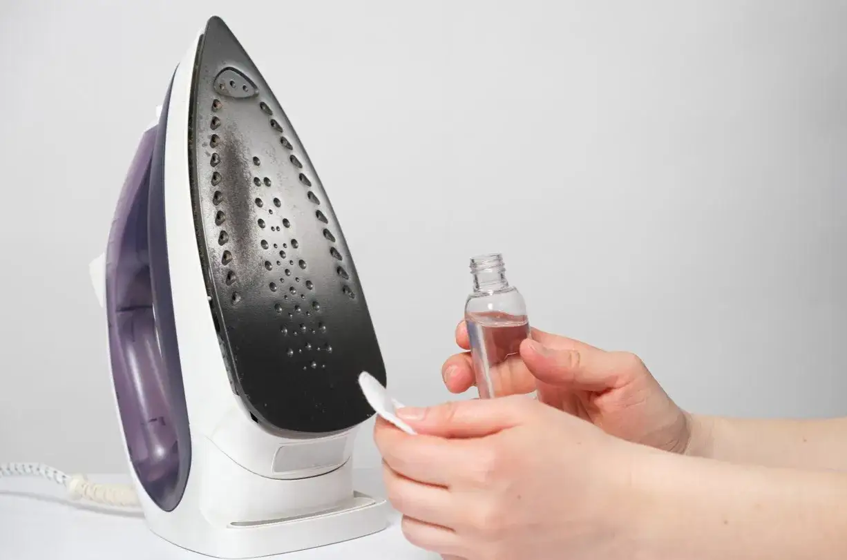 Nettoyer la semelle d'un fer à repasser tachée de colle avec un coton imbibé de produit.