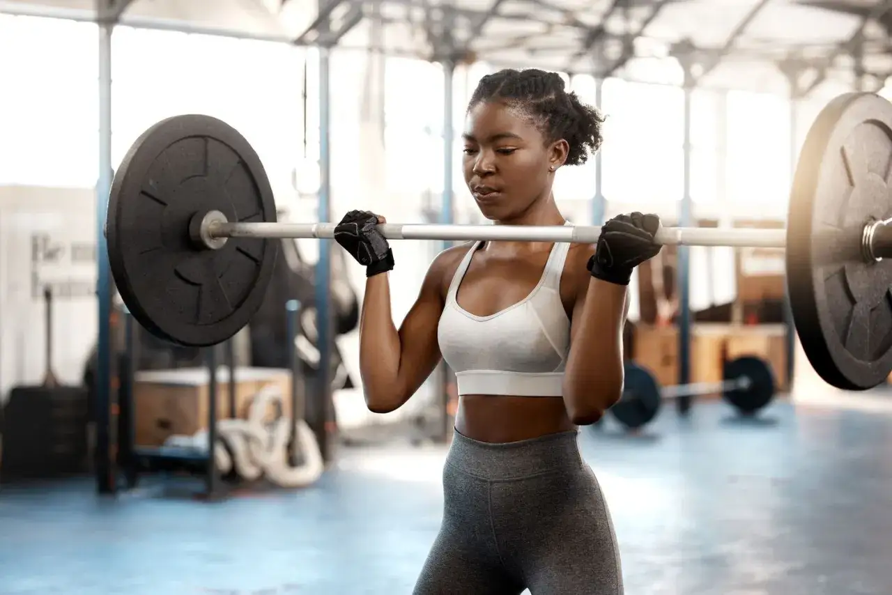 Eine Frau hebt eine Langhantel im Fitnessstudio, konzentriert auf ihren 1 satz training.