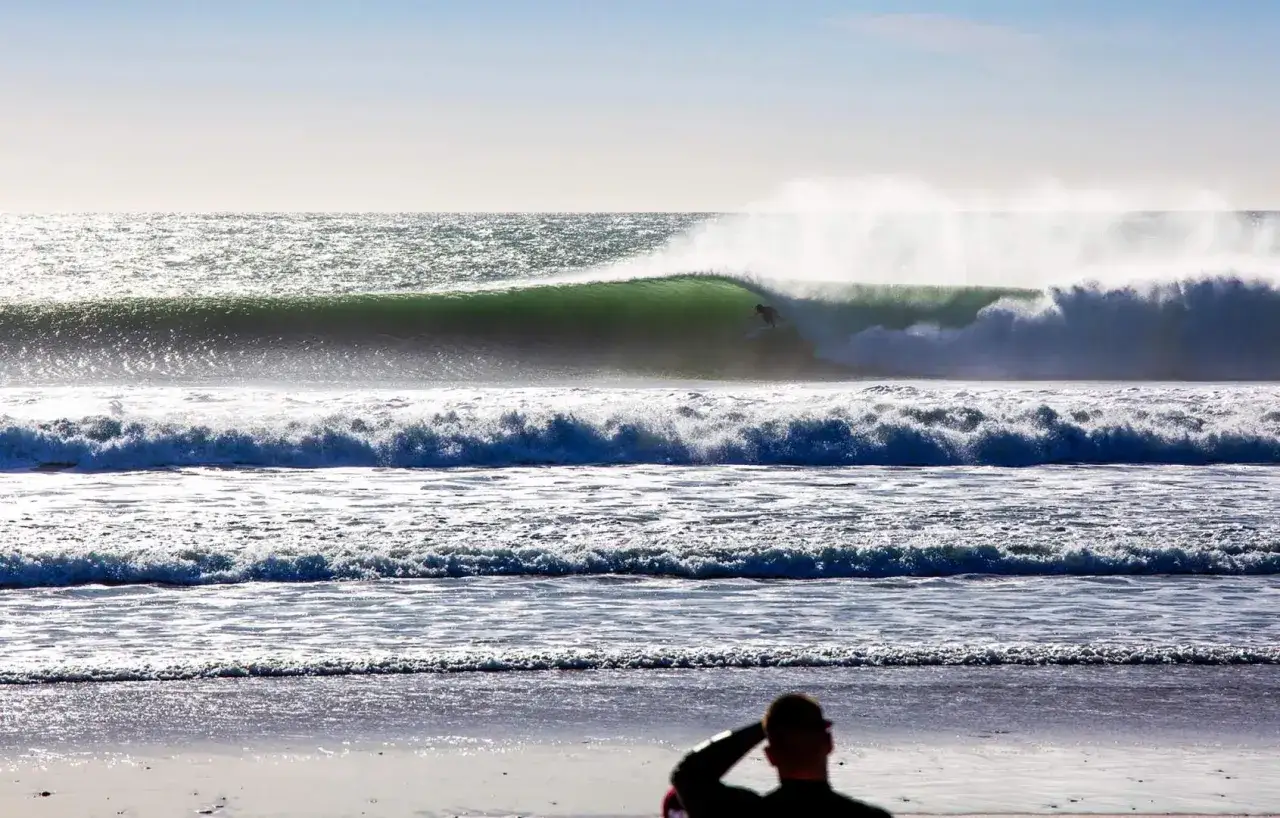 Surfer reitet eine gr&uuml;ne Welle im El Palmar Surfen. Ein Zuschauer beobachtet vom Strand aus.