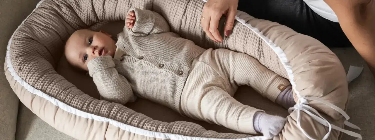 Ein **hochsensibles Baby** liegt in einer kuscheligen Nestchen. Die sanften Farben und die weichen Stoffe schaffen Geborgenheit für das kleine Wesen.