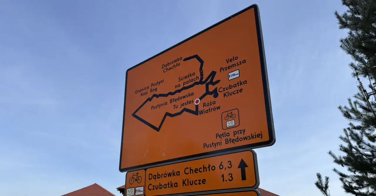 Pomarańczowa tablica z mapą szlaków rowerowych Velo Przemsza. Widać trasę przez Pustynię Błędowską, Dąbrówkę Chechło i Czubatkę Klucze.