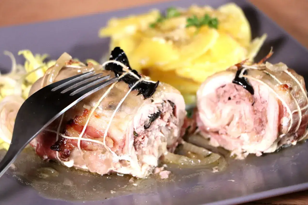 Une cuisse de poulet farcie, savoureusement roul&eacute;e et ficel&eacute;e, est pr&ecirc;te &agrave; &ecirc;tre d&eacute;gust&eacute;e avec des pommes de terre gratin&eacute;es.