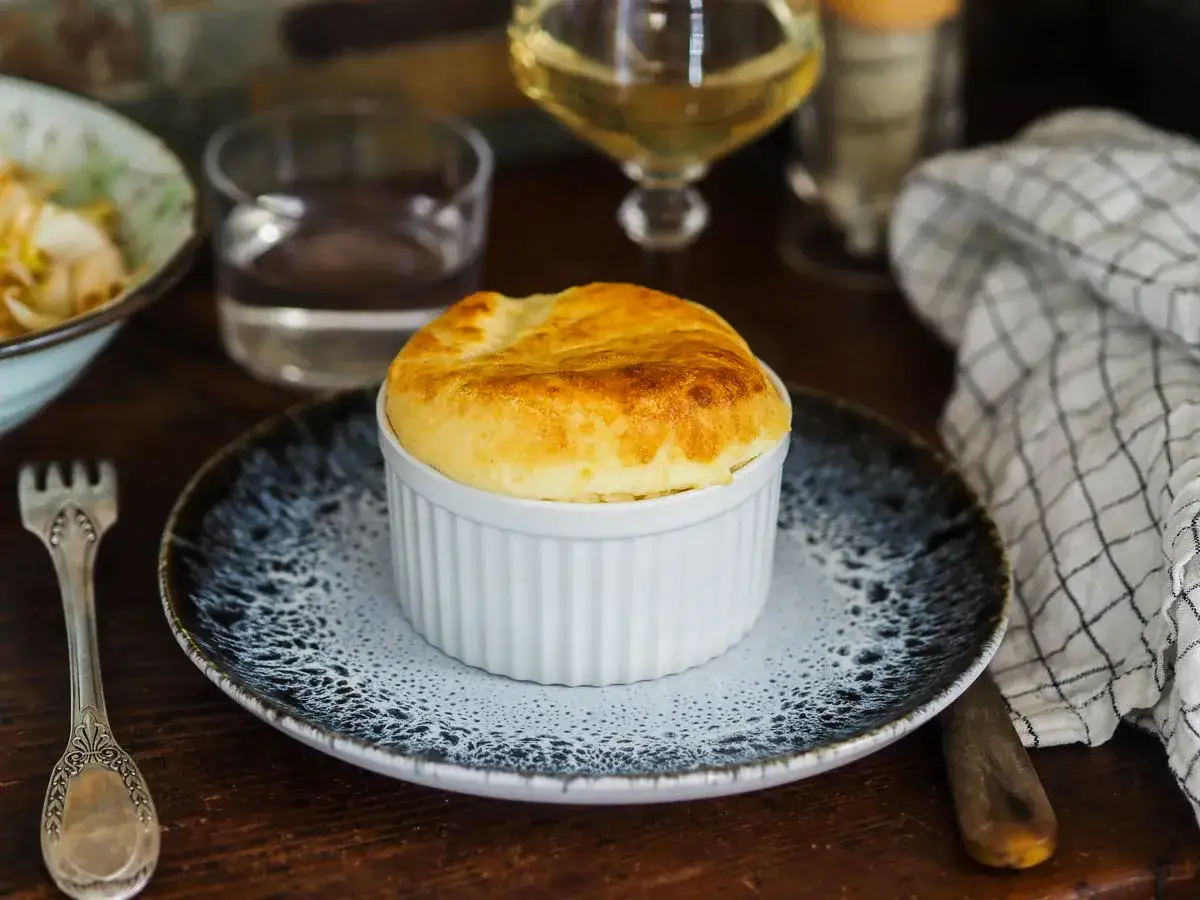 Souffl&eacute; sal&eacute; dor&eacute; dans un ramequin blanc, pr&ecirc;t &agrave; &ecirc;tre d&eacute;gust&eacute;. Une recette de souffl&eacute; sal&eacute; facile pour un repas savoureux.
