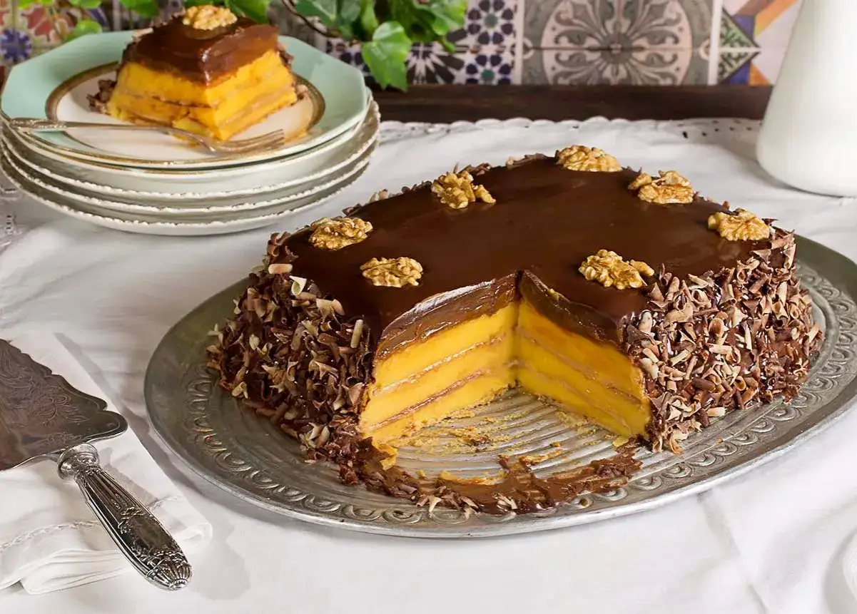 La tarta de la abuela, con capas de crema y chocolate, decorada con nueces y virutas de chocolate. ¡Un postre casero irresistible!