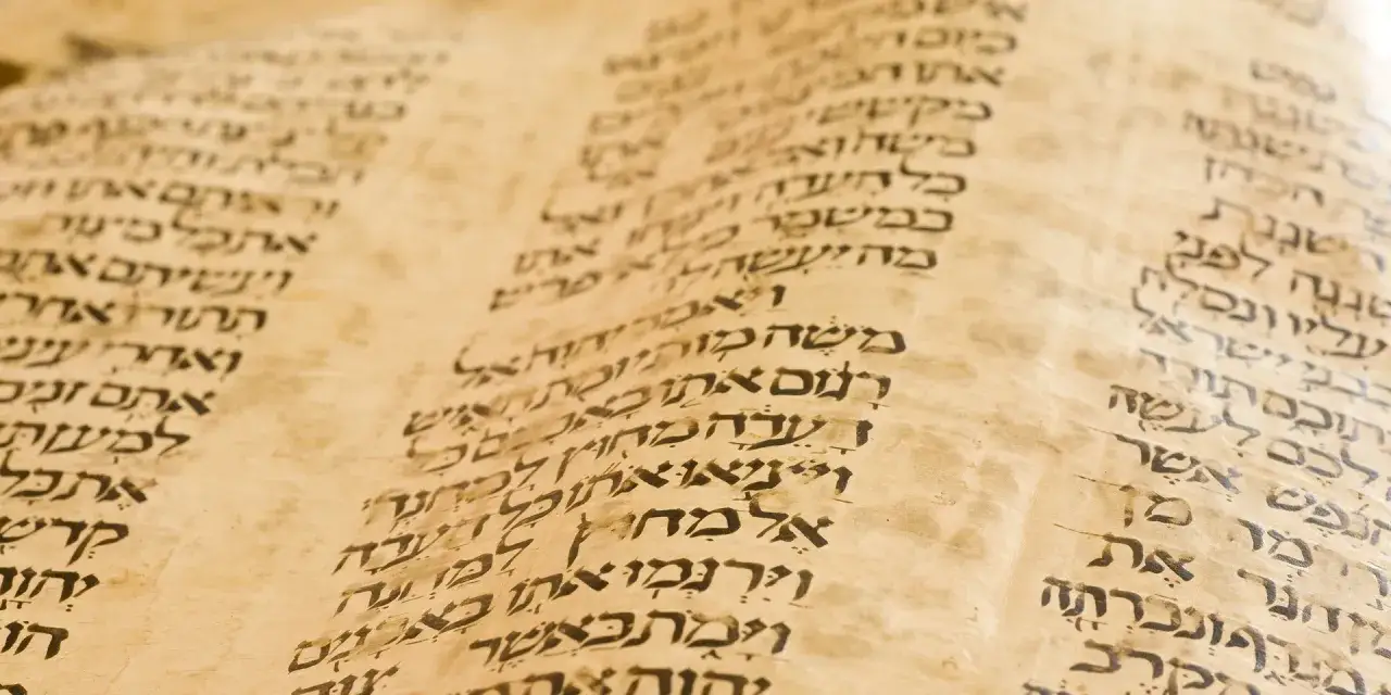 Detalle de un pergamino antiguo con escritura hebrea, que nos recuerda qué es la Biblia y su antigüedad.