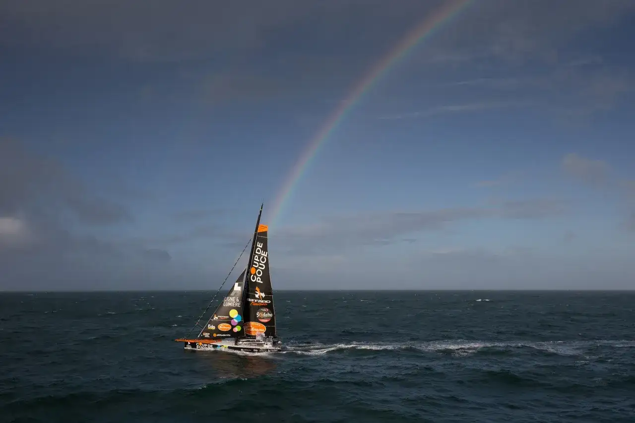 Segelboot mit Regenbogen über dem Meer, ein Teilnehmer des Vendée Globe.