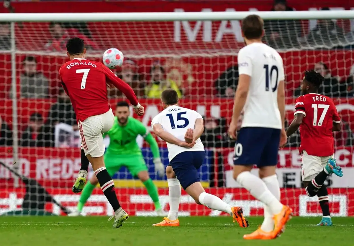 Piłkarz Ronaldo w czerwonej koszulce z numerem 7 wykonuje strzał głową. Jego **wzrost** pozwala mu na takie akcje. Bramkarz w zielonym stroju jest gotowy do obrony.