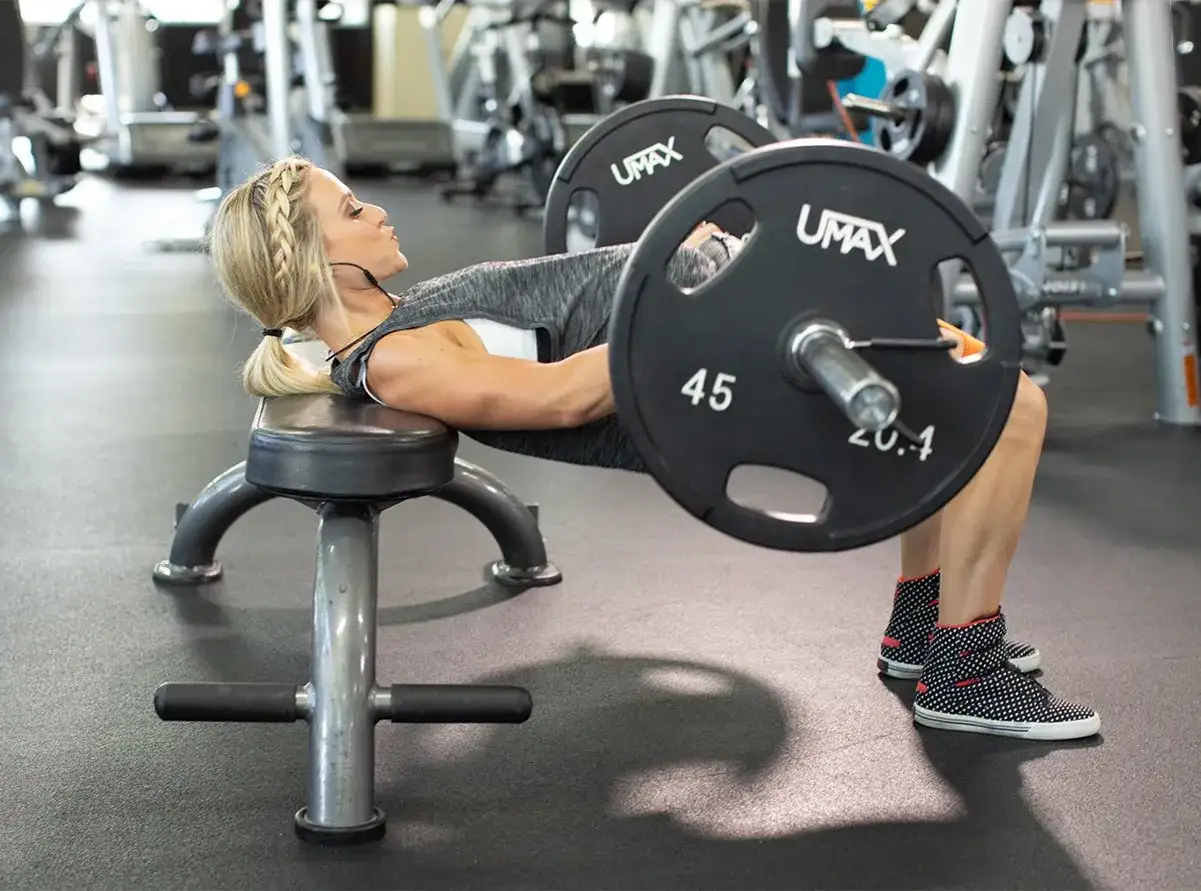 Donna esegue un hip thrust con bilanciere, un esercizio chiave per capire quanto tempo ci vuole per rassodare i glutei.