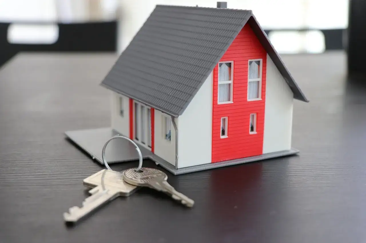 Maquette de maison rouge et blanche avec des clés, symbolisant un projet de crédit immobilier avec travaux.