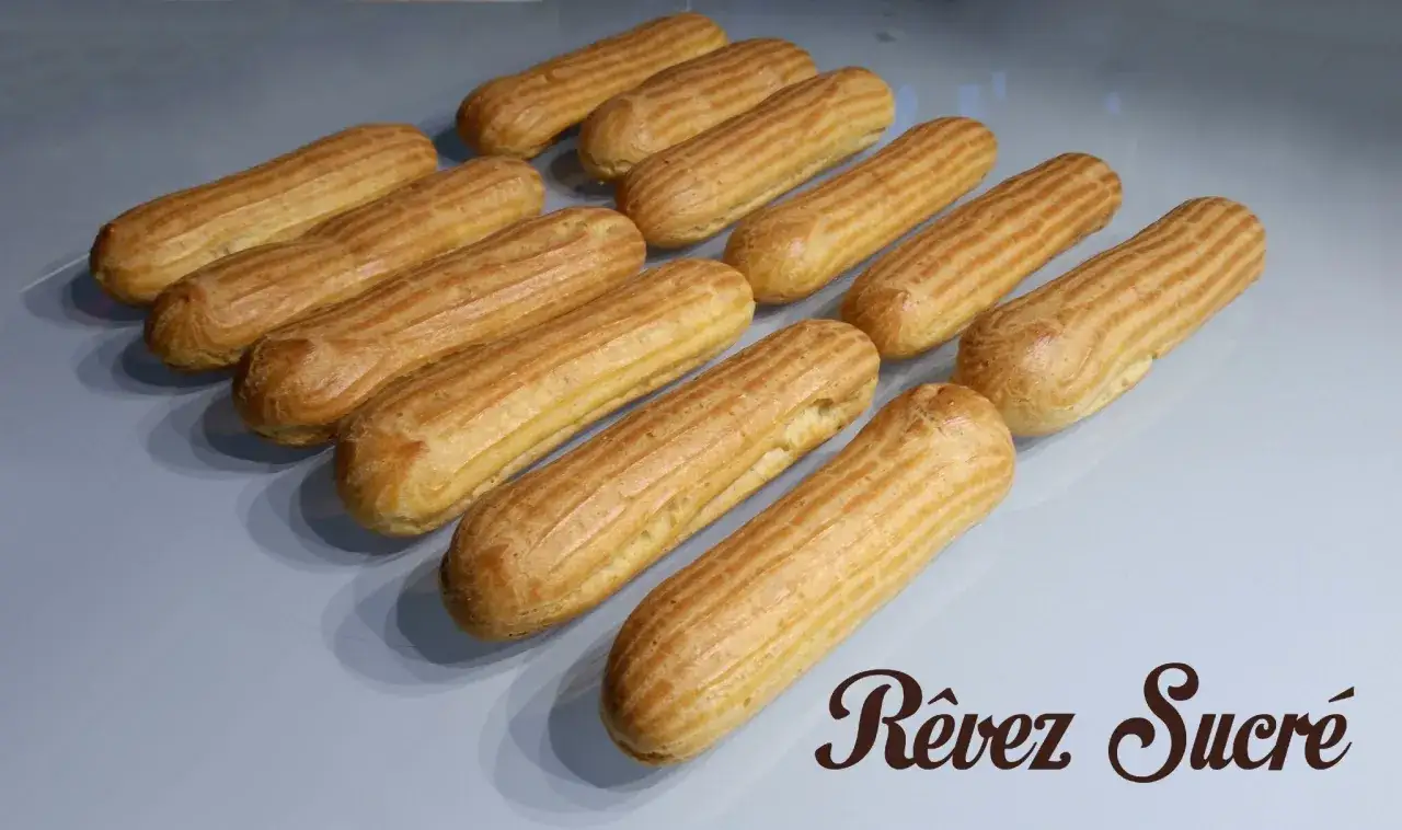 Douze &eacute;clairs dor&eacute;s, pr&ecirc;ts &agrave; &ecirc;tre garnir. La p&acirc;te &agrave; choux est parfaitement cuite, pr&ecirc;te pour un r&ecirc;ve sucr&eacute;.