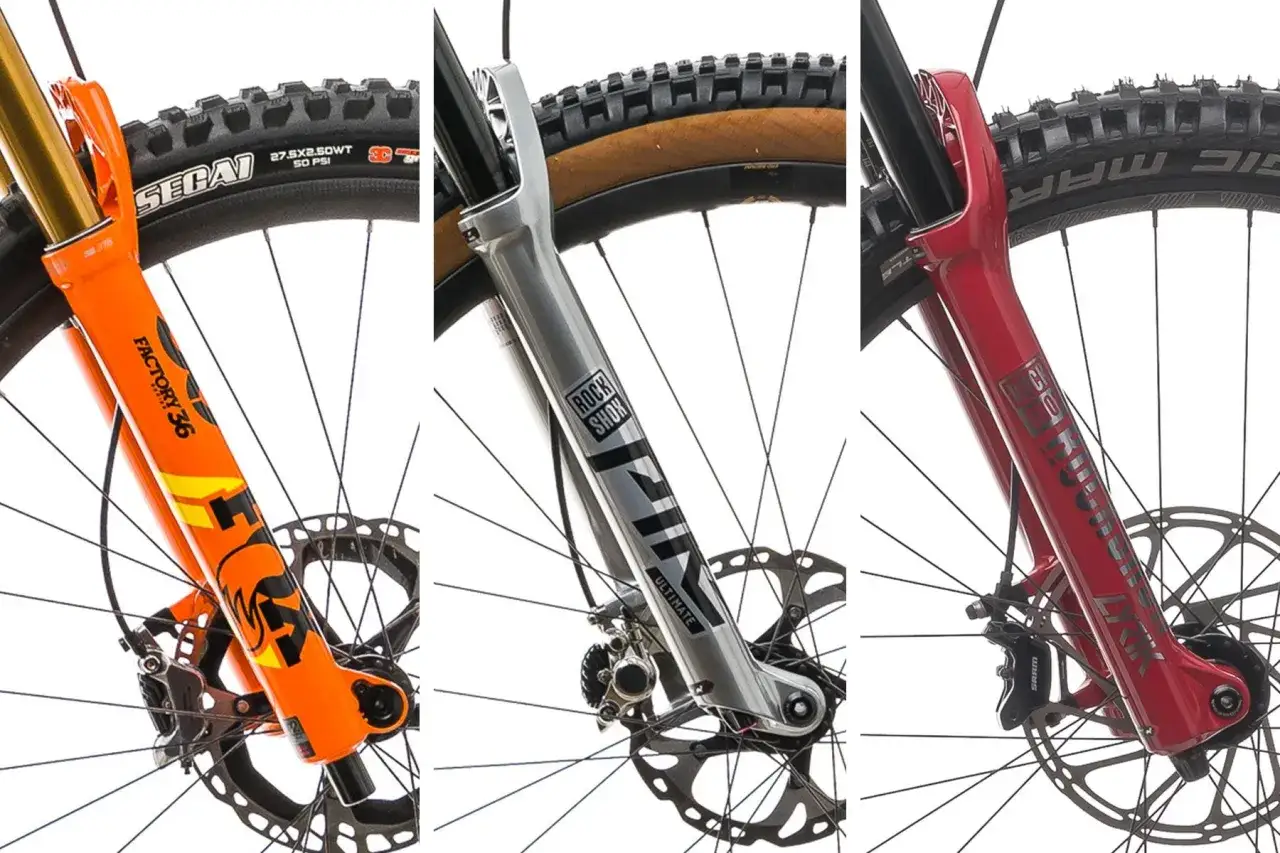 Trzy widelce rowerowe: pomarańczowy Fox, srebrny Rock Shox Lyrik i czerwony Rock Shox. Wyb&oacute;r między amortyzatorem powietrznym czy sprężynowym.