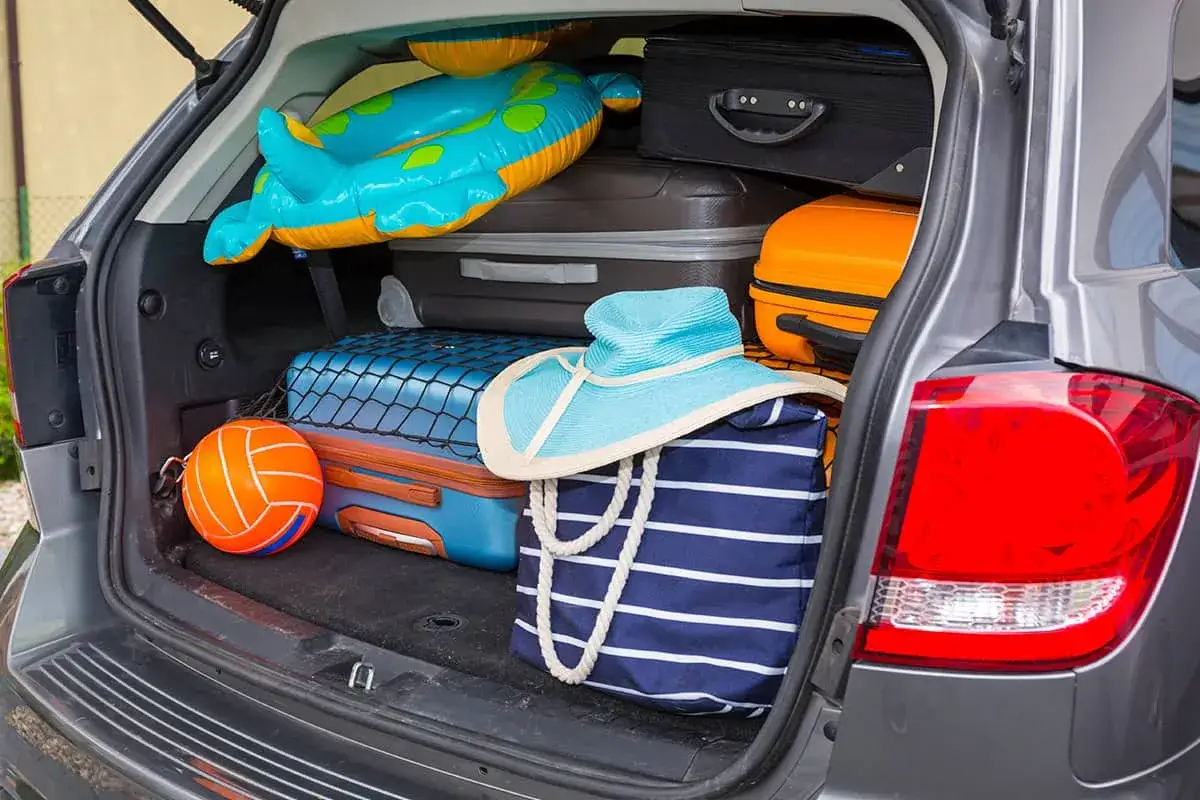 Maletero de un Fiat 500 lleno de equipaje para vacaciones: maletas, un flotador, un balón y un sombrero.