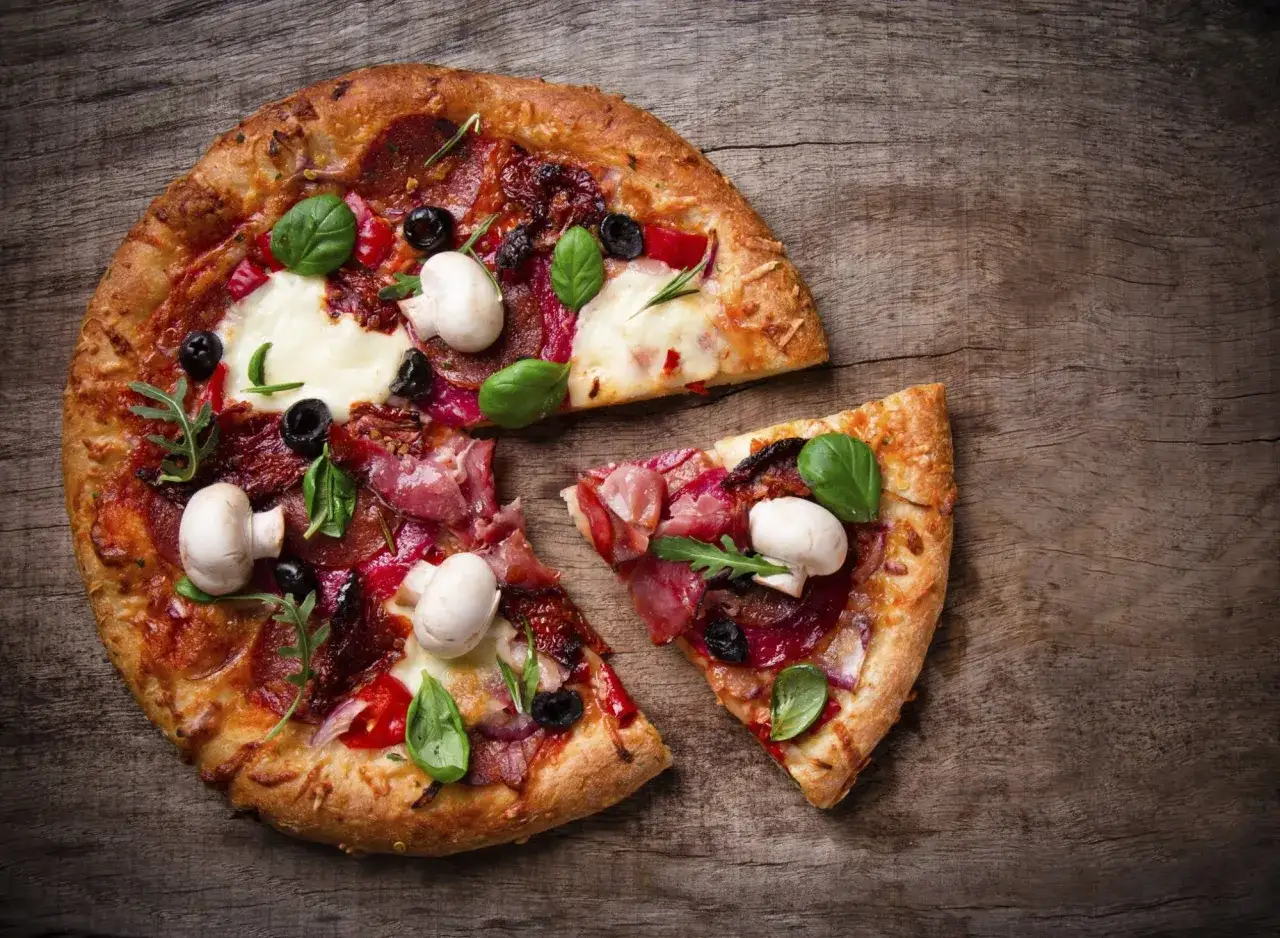 Eine k&ouml;stliche Pizza Semola mit Pilzen, Oliven und frischem Basilikum auf rustikalem Holz.