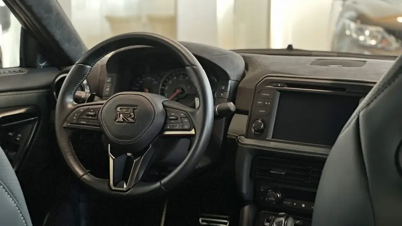 Wnętrze sportowego Nissana R35 z kierownicą GT-R i ekranem multimedialnym.