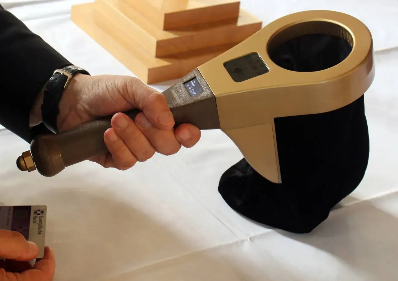 Moderne Spende in der Kirche: Ein Ger&auml;t sammelt bargeldlose Gaben. Eine Hand h&auml;lt den Spenden-Scanner, daneben eine Bankkarte.