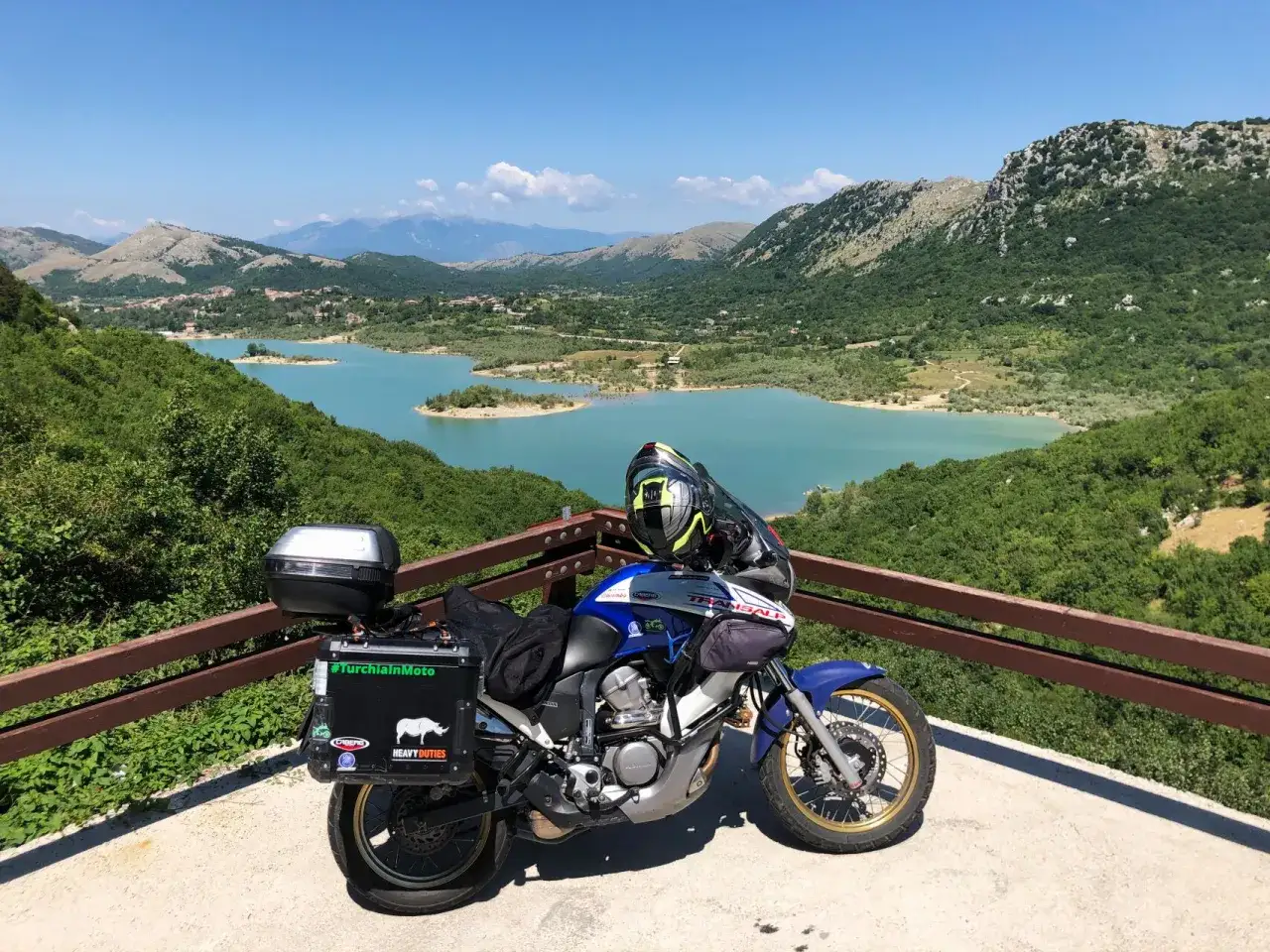 Moto pronta per avventurosi giri in moto nel Lazio, con un panorama mozzafiato sul lago e le montagne.