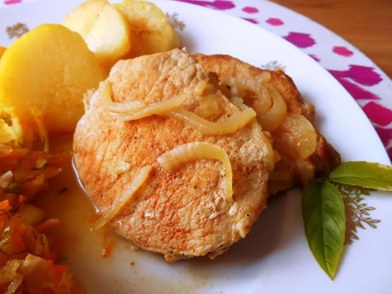 Pyszny schab w cebuli, idealny na niedzielny obiad, podany z ziemniakami i surówką.