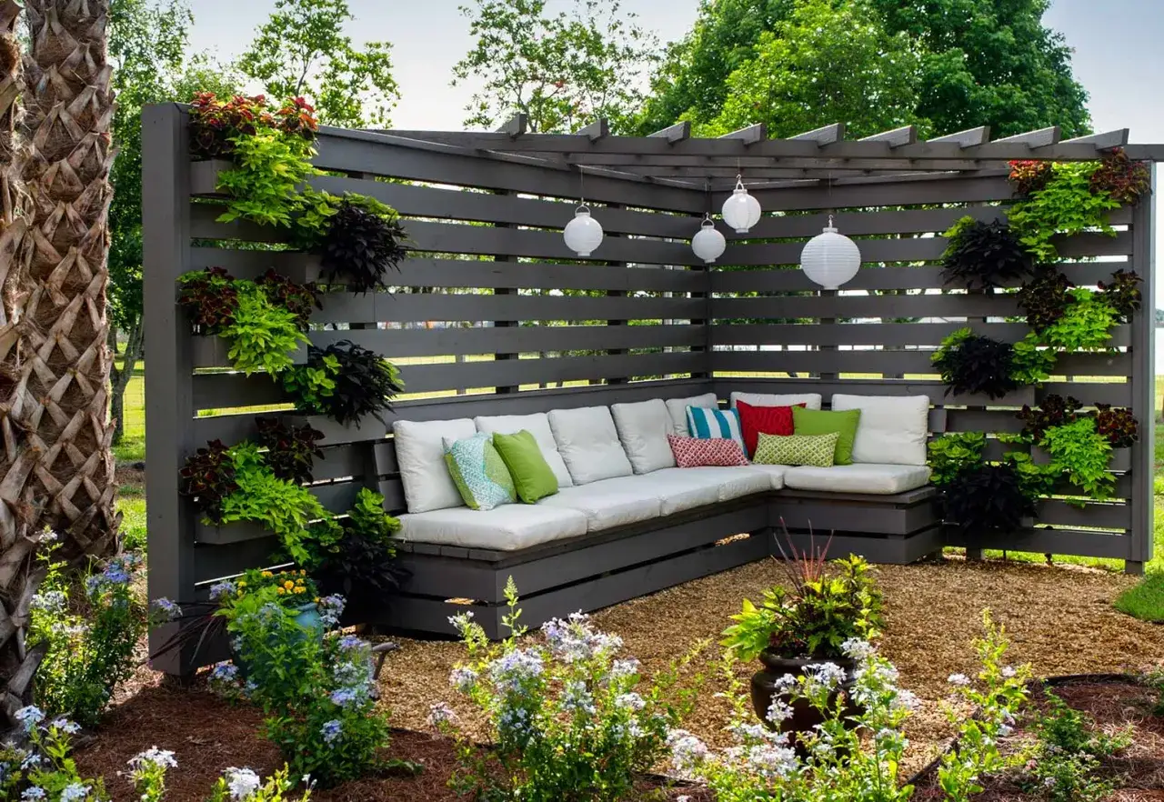 Rinc&oacute;n de patio con sof&aacute; modular y plantas colgantes. Una idea genial para decorar patio sin dinero, con cojines coloridos y farolillos.