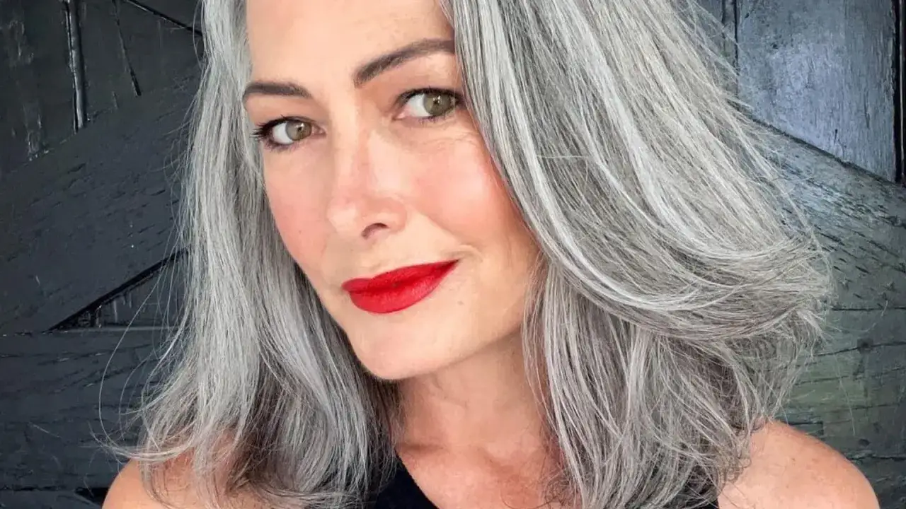 Donna con splendidi capelli grigi, labbra rosse e sguardo intenso.
