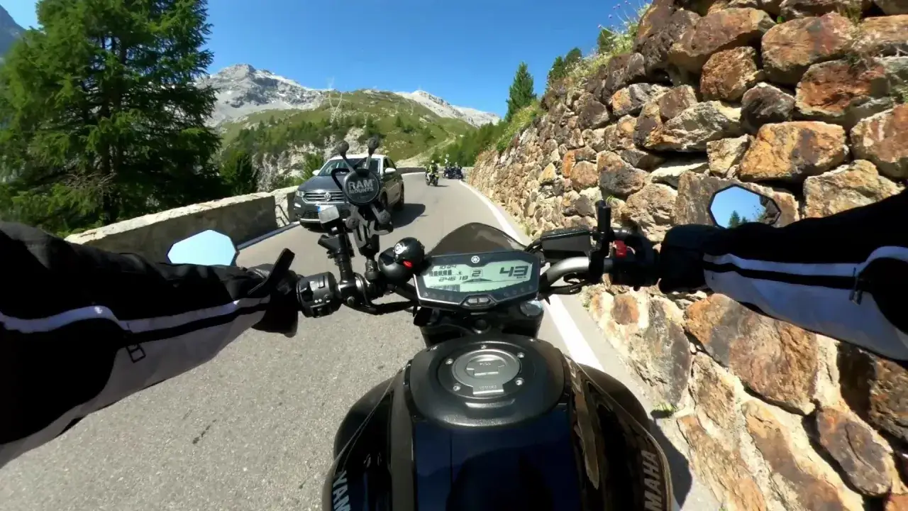 Motociclista sui tornanti dello Stelvio, con auto e altre moto in vista. Paesaggio alpino mozzafiato.
