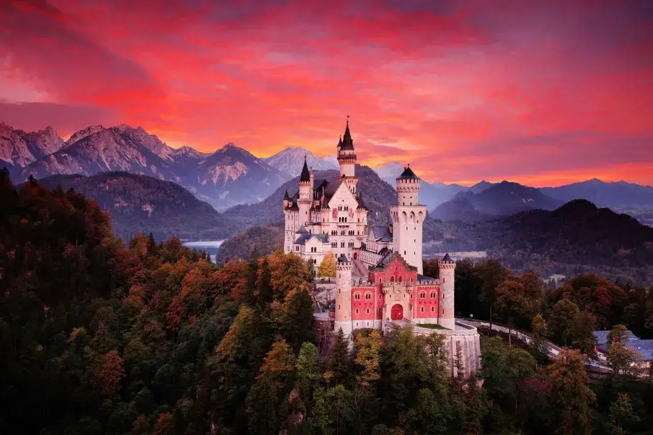 Bajkowy zamek Neuschwanstein, jeden z najpiękniejszych zamków w Niemczech, wznosi się na tle dramatycznego, czerwonego nieba.