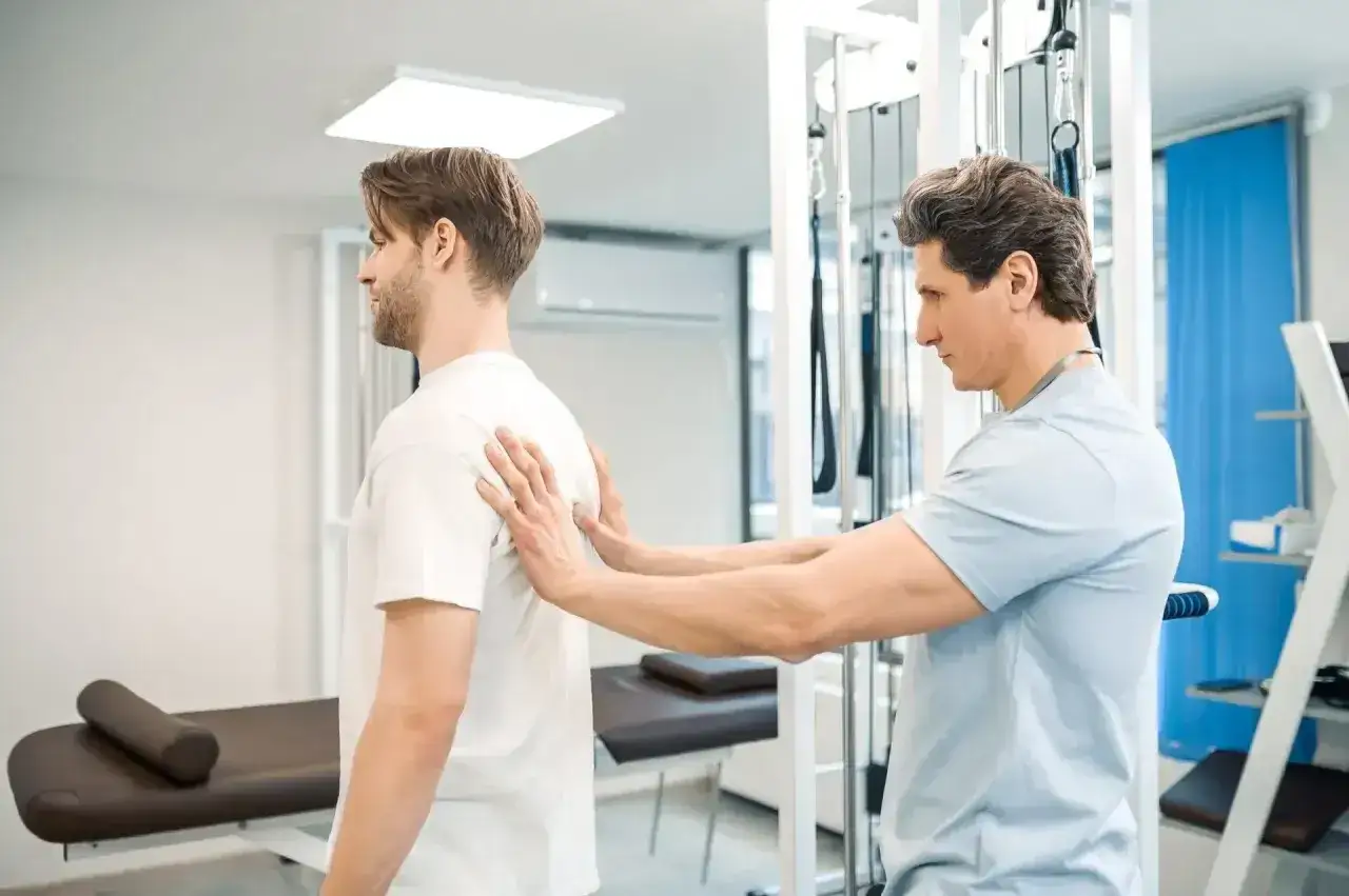 Fizjoterapeuta bada plecy pacjenta, co jest częścią rehabilitacji i pokazuje, jak wygląda pobyt w szpitalu uzdrowiskowym.