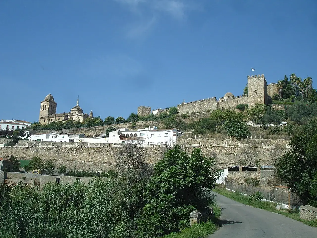 Blick auf die historische Stadt Jerez de los Caballeros mit einer imposanten Burg und einer Kirche auf einem H&uuml;gel.