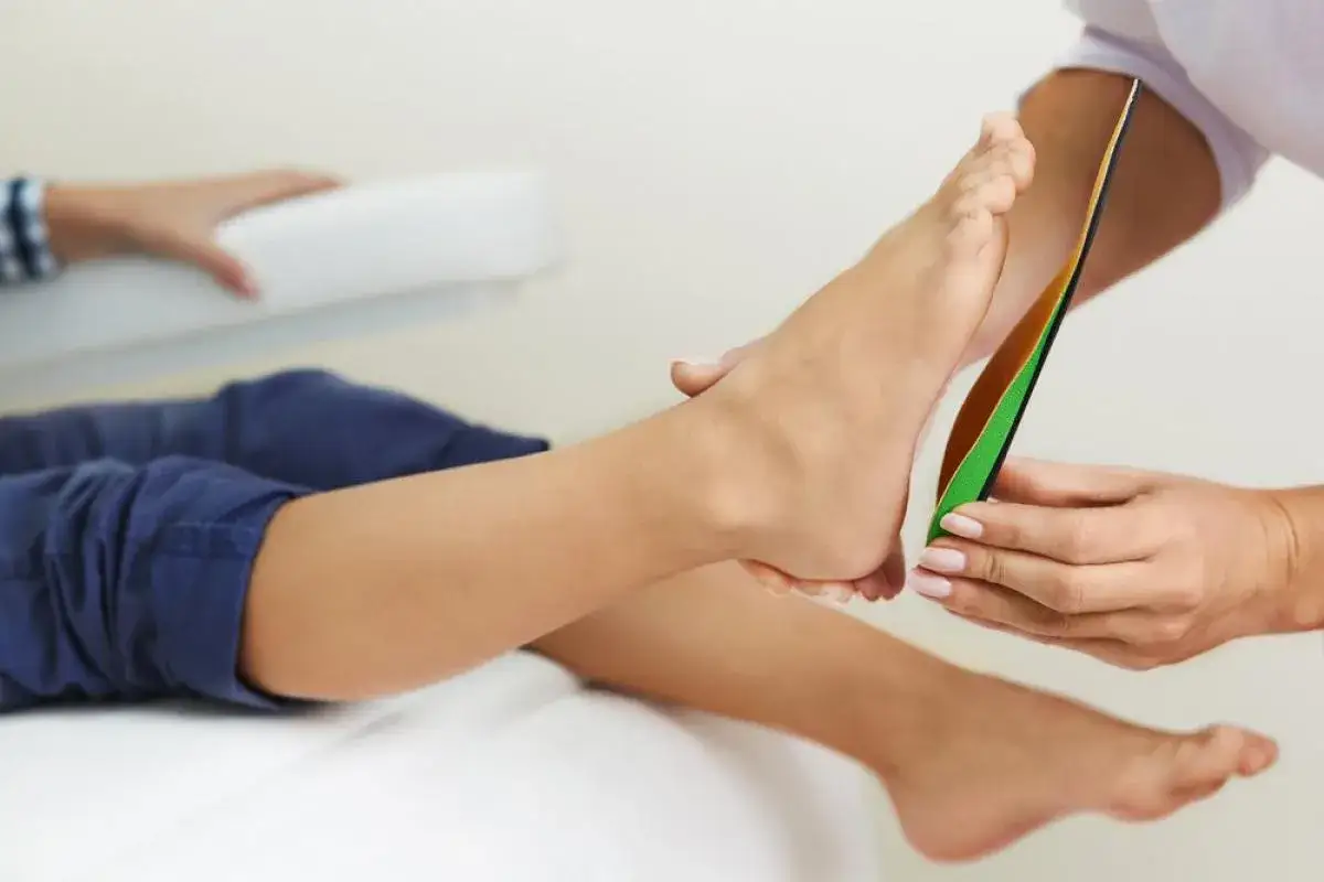 Un podologue ajuste des semelles orthop&eacute;diques sur le pied d'un patient pour un confort optimal.