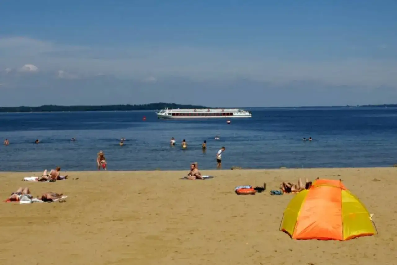 Sonne, Sand und ein Schiff auf dem Wasser am Schweriner Strand. Menschen entspannen sich am Ufer und im kühlen Nass.